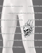 Burning skull tattoo shown on a man’s front thigh with exposed teeth, dark facial cavities, tall crown flames, curling side fire, and a vertical composition