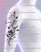 Climbing rose tattoo shown on a woman’s upper arm with rosebuds, swirling vine tendrils, loose black ink details, and whimsical botanical styling