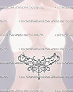 Feminine dragonfly tattoo shown on a woman’s stomach with broad ornamental wings, flowing botanical scrollwork, and a centered hanging jewel detail