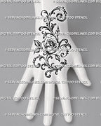 Filigree rose tattoo shown on the back of the hand with layered petals, decorative curls, acanthus-style leaves, and ornament extending toward the wrist