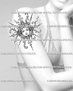 Filigree sun face tattoo shown on a woman’s upper arm with crown-like ornament, acanthus curls, baroque scrollwork, and sharp sunburst rays