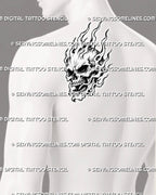 Flaming skull tattoo shown on a man’s back shoulder with a three-quarter skull, open jaw, layered flames, hollow fire details, and illustrative black-and-grey shading