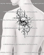 Gothic filigree skull tattoo shown on a man’s shoulder with dark bone shading, curling acanthus ornament, pointed extensions, and suspended diamond details