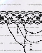Close-up of gothic lace garter tattoo showing scalloped floral lace, bead-chain drapes, hanging charms, ornamental scrollwork, and pointed cross pendant