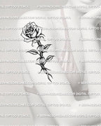 Rose with barbed wire tattoo shown on women’s arm placement with shaded flower and twisted stem