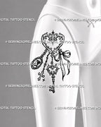 Vintage jewelry tattoo shown on a woman’s front thigh with a filigree heart key ring, antique key, cameo, cross charm, bow, and decorative chains