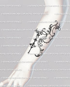 Elegant baroque filigree tattoo stencil displayed on the forearm, showing pendant-inspired gothic blackwork line art pattern. 