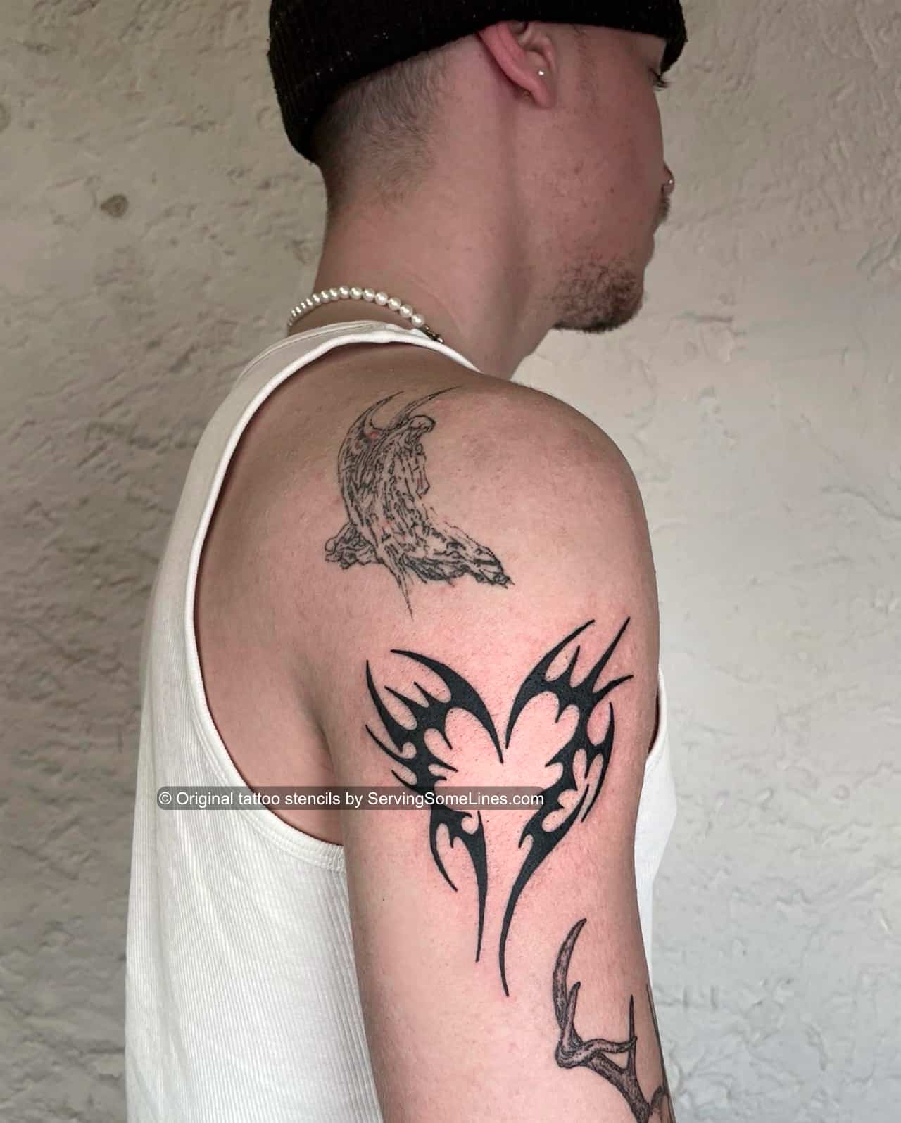 Black tribal heart tattoo shown on mens upper arm placement, bold neotribal heart silhouette with sharp points, clean black fill.