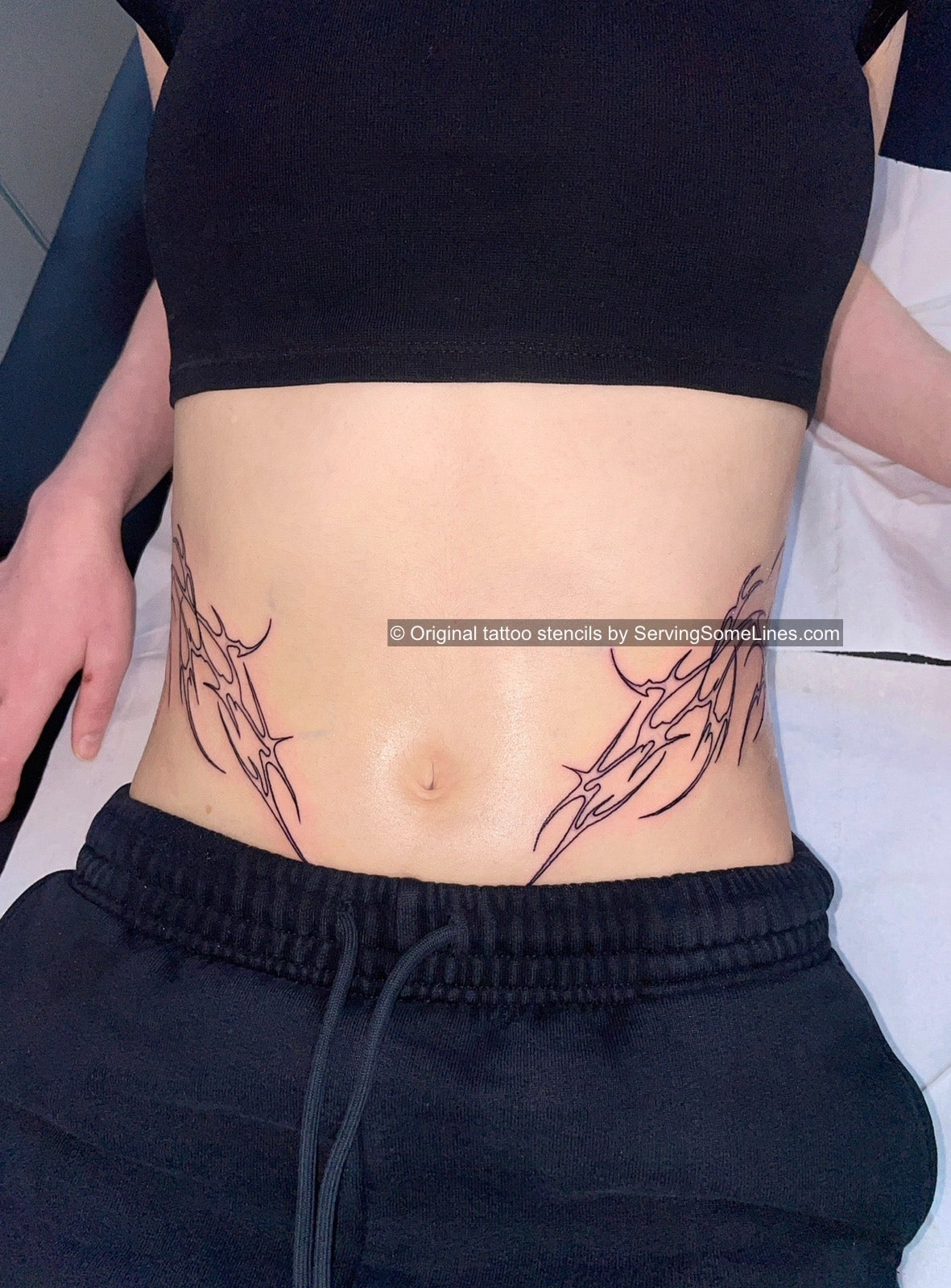Cyber-tribal waist tattoo with 2 symmetrical neotribal shapes on stomach and sides, custom cybersigilism outline design for women.