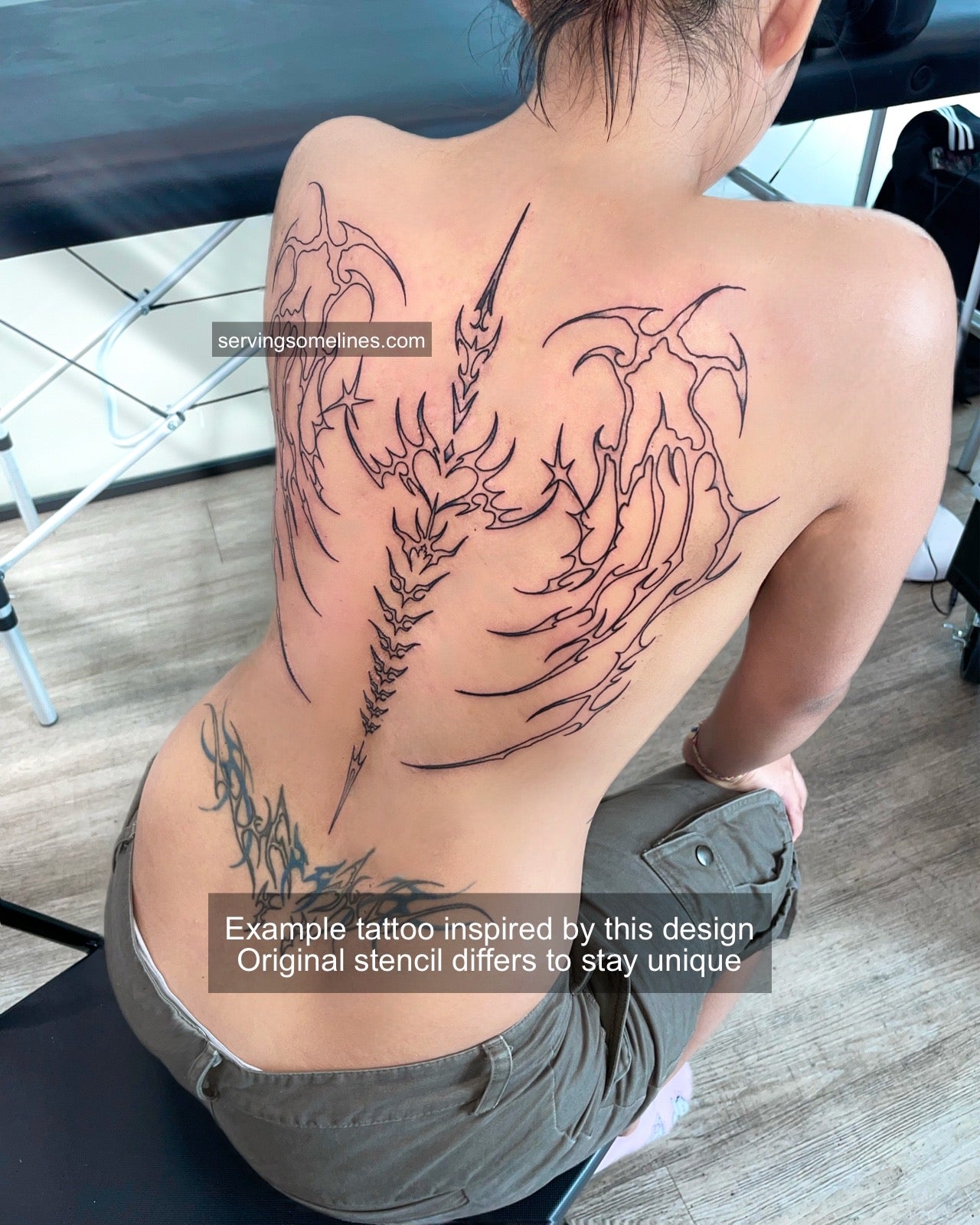 Tattooed back showing cybersigilism and neotribal skeletal spine wings, real example of spiky backpiece tattoo design from ServingSomeLines.