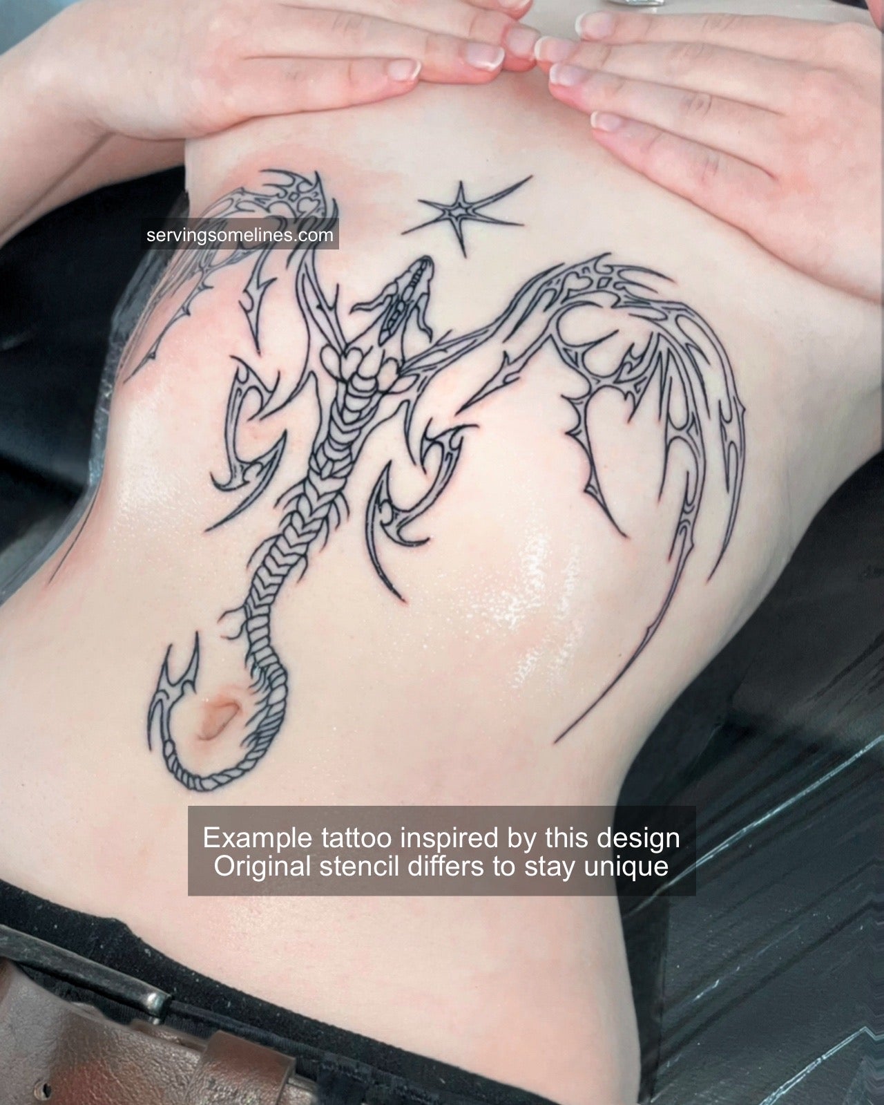 Tattooed cyber dragon design on feminine sternum and stomach, sharp neotribal wings with gothic symmetry and fine cybersigilism detail.
