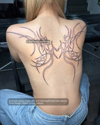 Real healed tattoo based on this digital stencil shown on a girl’s upper back with a centered heart-shaped wing layout