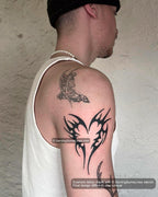 Tattooed on mens upper arm placement example, heart tribal tattoo stencil with black tribal heart tattoo curves and negative space.