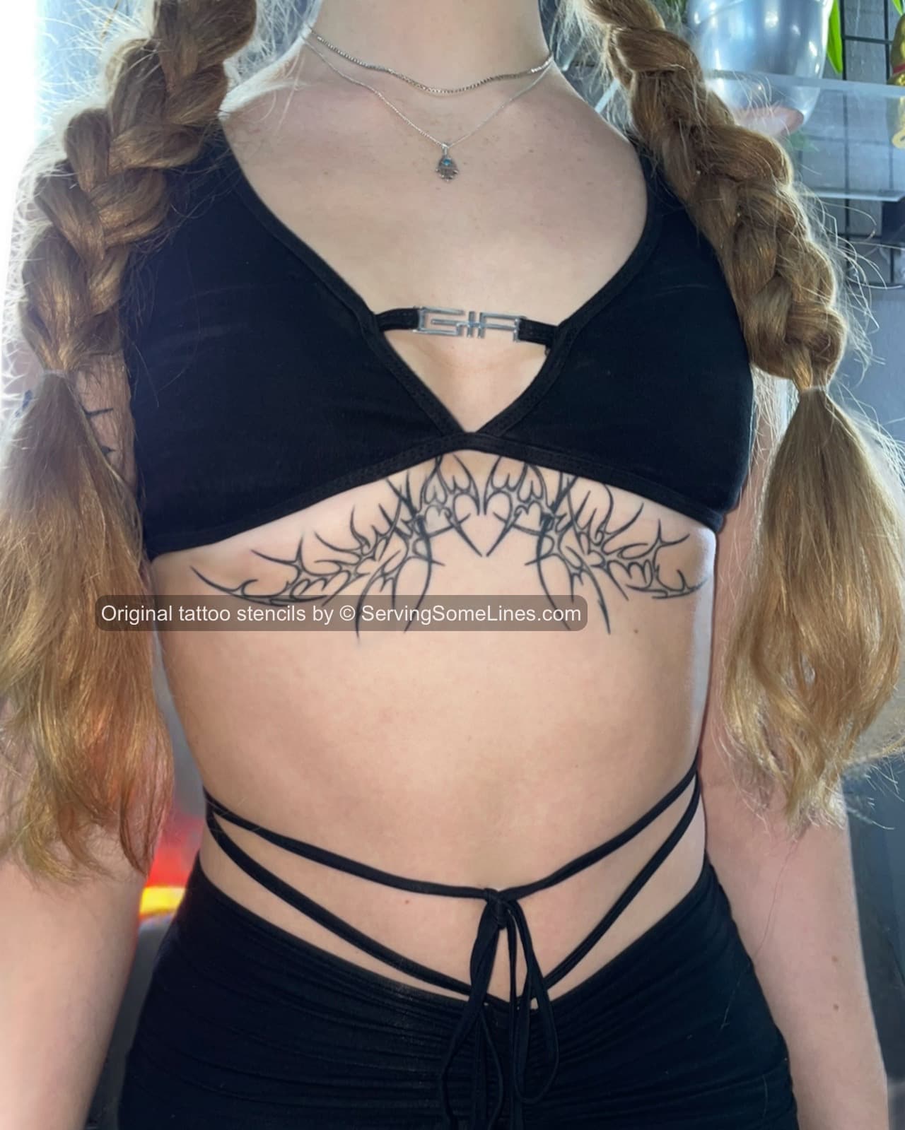 ornamental underbust tattoo on woman with fineline neotribal heart motif shaped to follow chest curves, rib contour, and lower torso placement