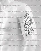 Devotional cross tattoo stencil shown on men's bicep, with praying hands focal point, clear base cross, and readable linework.
