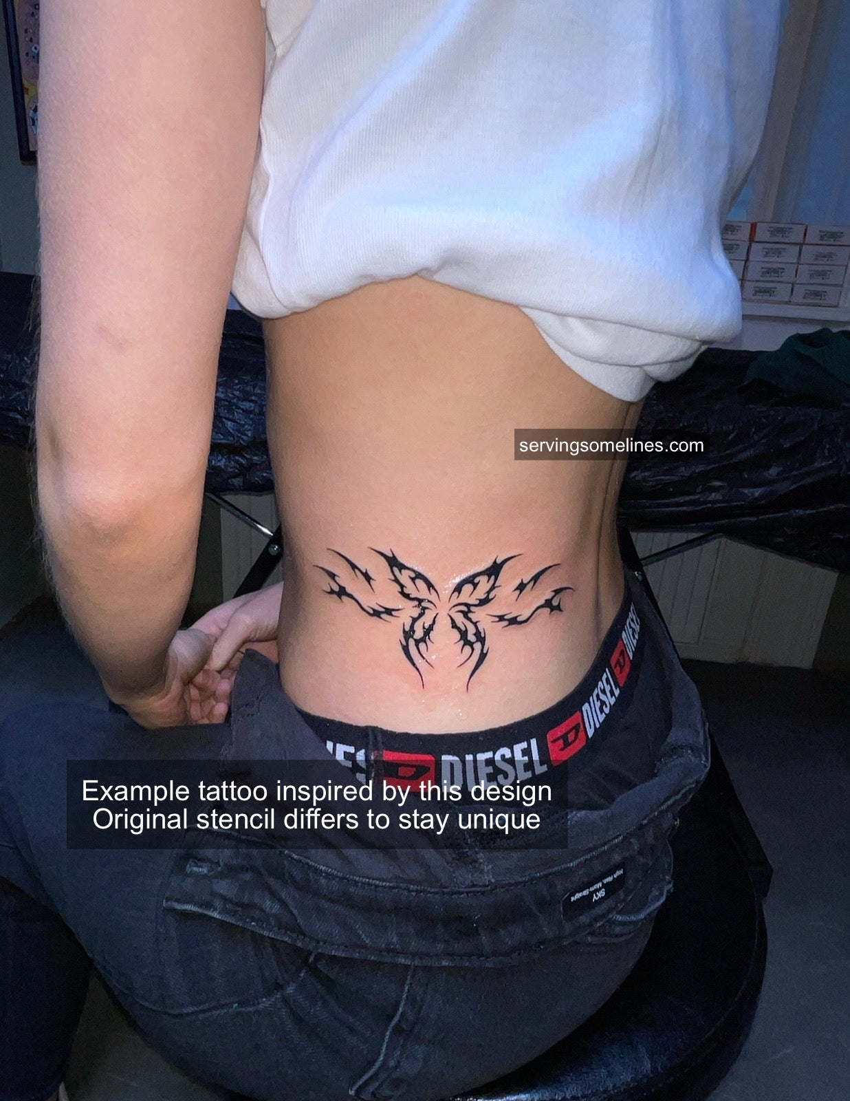 Real tattoo example on girl’s side stomach showing cyber-tribal butterfly with flaming neotribal wings, delicate Y2K black linework.