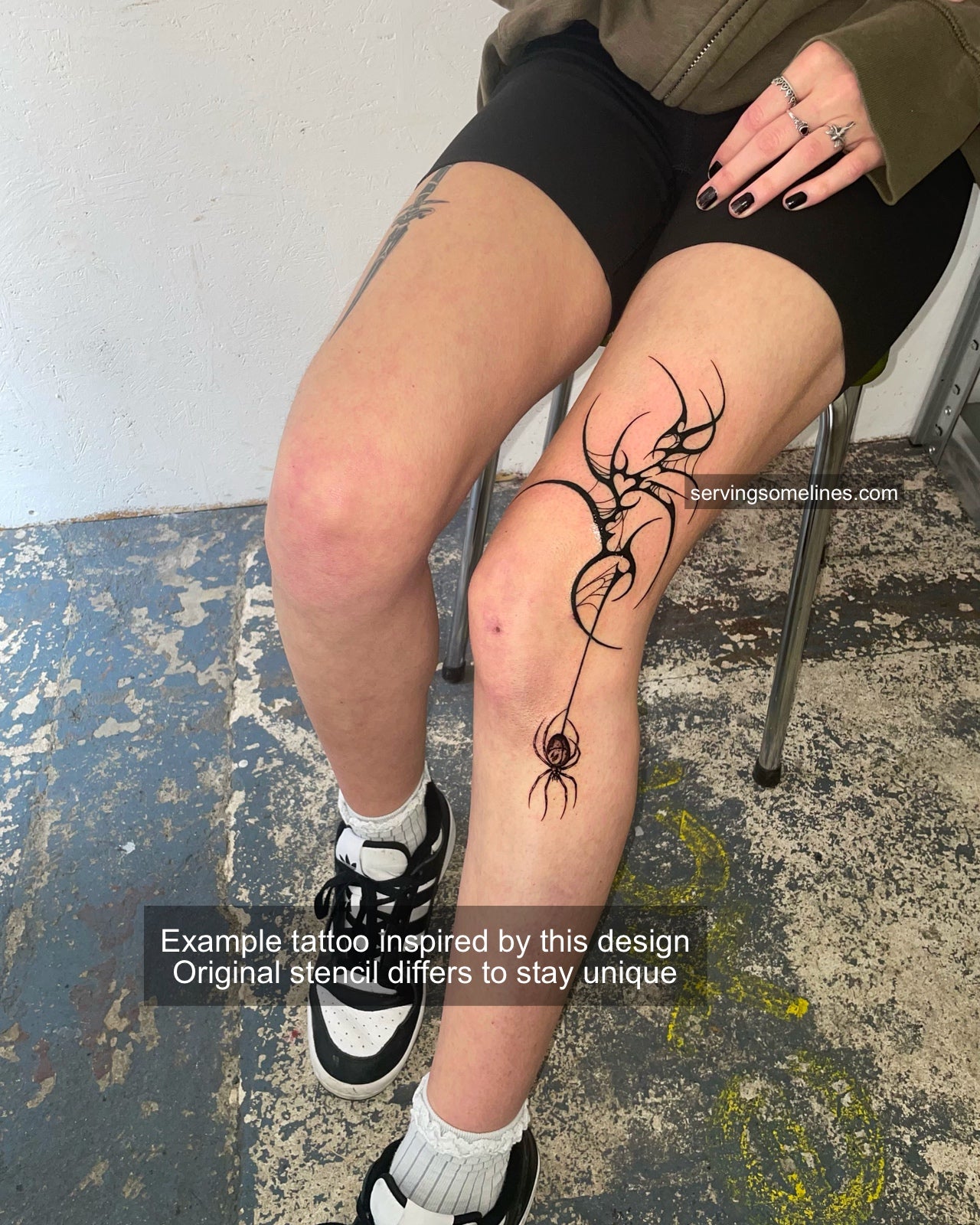 Witchy spiderweb tattoo flash displayed on side knee placement, fine black lines and tribal spikes in gothic cyber style.