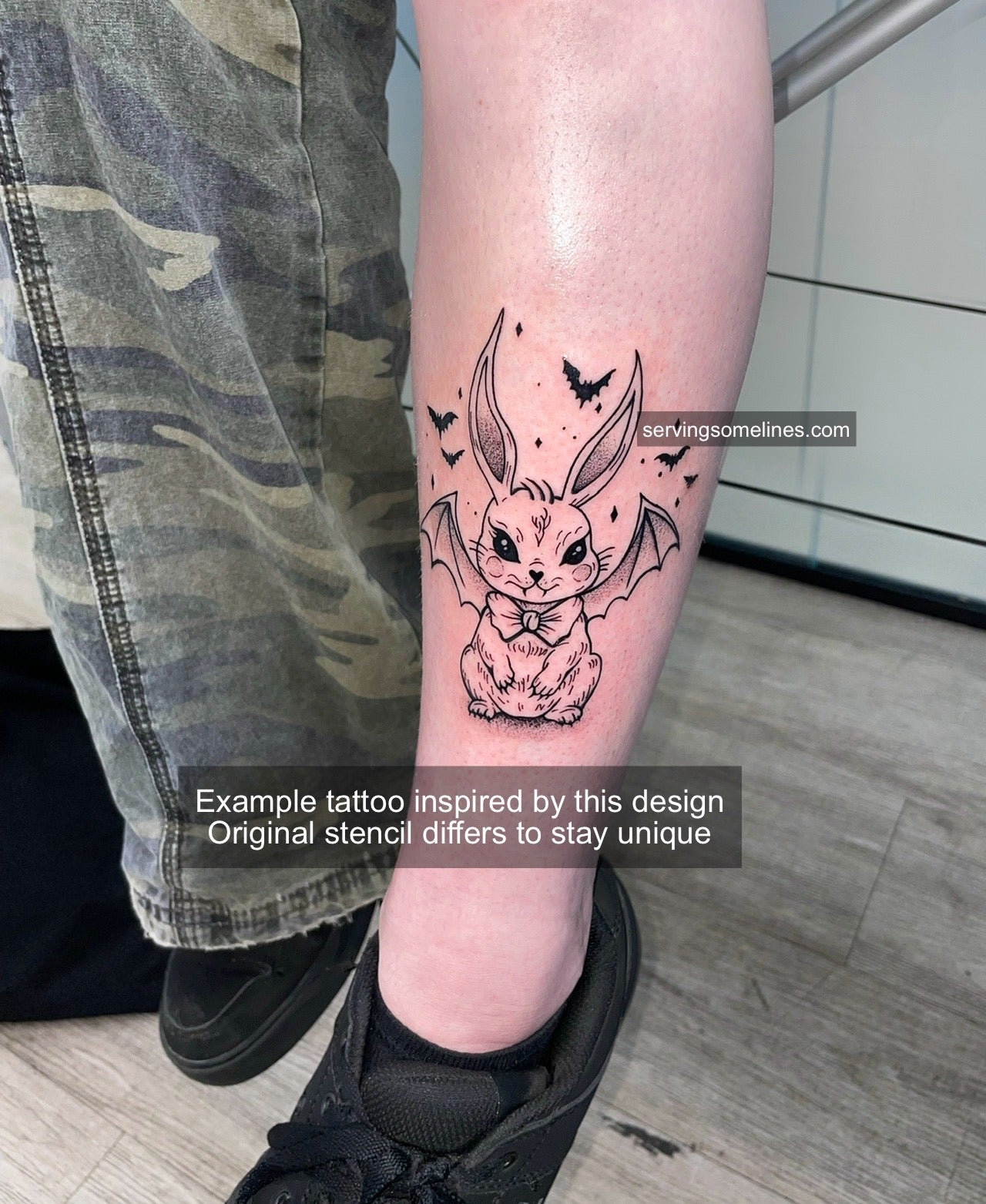 Tattoo example of vampire bunny on leg, spooky gothic bunny with wings and fangs in fine blackwork line art.