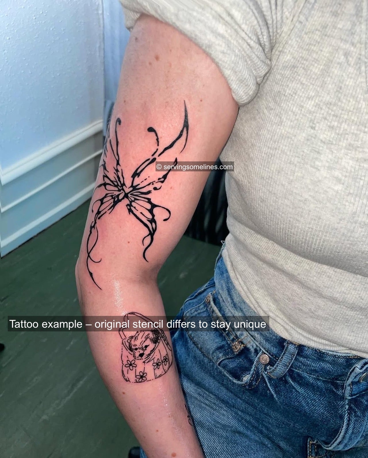 Cyber-sigil butterfly stencil tattooed on woman’s arm, small fairycore ornamental linework design with dark heart center. 